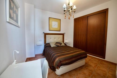 1 dormitorio con cama y lámpara de araña en Aires de cazalla, en Cazalla de la Sierra