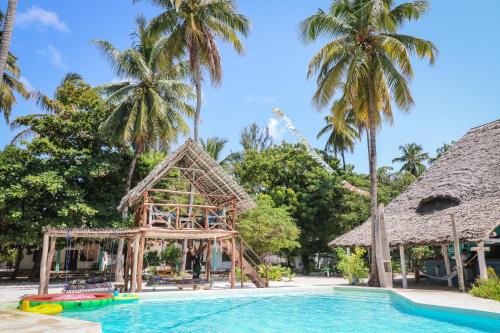 uma piscina num resort com escorrega e palmeiras em New Teddy's on the Beach em Jambiani