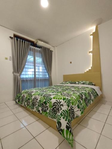 a bedroom with a green and white bed with a window at Airtown Guest House in Jetis