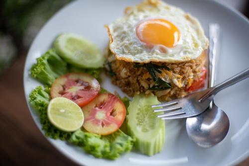 a plate of food with a fried egg and vegetables at Tarnsiri Boutique Resort in Kanchanaburi