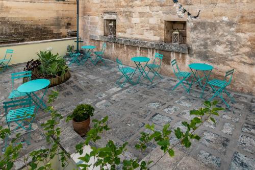 um pátio com mesas azuis, cadeiras e plantas em Damasa Rooms em Lecce