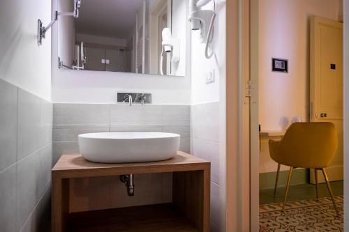 a bathroom with a white sink and a yellow chair at Damasa Rooms in Lecce