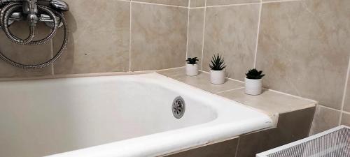 baño con bañera blanca con 3 plantas. en Martina, en Supetar
