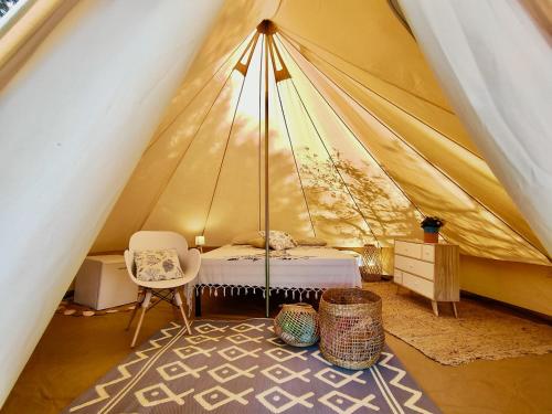um quarto numa tenda com uma cama e uma cadeira em La Tenda a Marina Serra di Casa Camilla Journey em Marina Serra