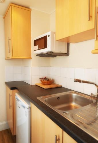 a kitchen with a sink and a microwave at The Portpatrick Hotel by Compass Hospitality in Portpatrick
