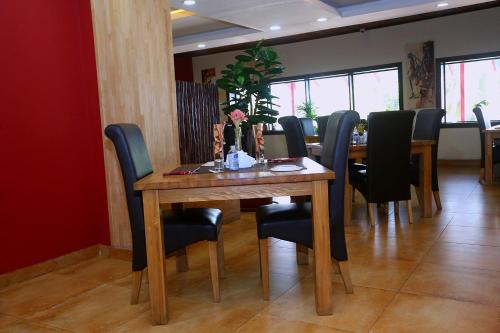 a dining room with a wooden table and black chairs at The Cape Hotel in Monrovia