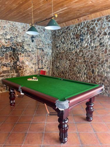a green pool table in a room with a stone wall at Calligraphy Hotel and Cottages in Mtsvane Kontskhi
