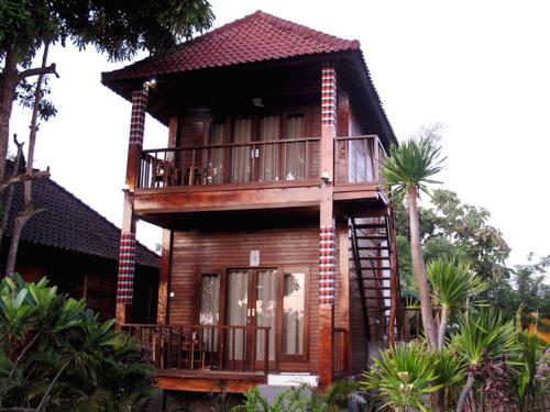 una casa in legno con balcone e alberi di Dmas Huts Lembongan a Nusa Lembongan