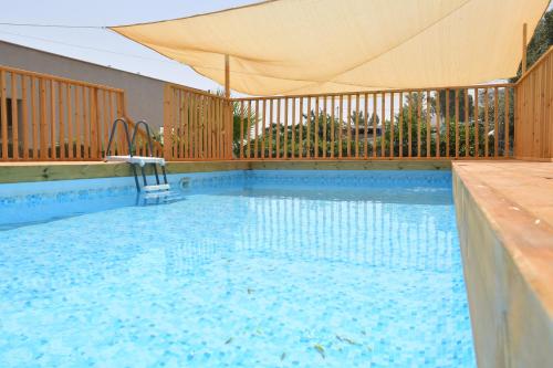 a large swimming pool with a tan umbrella over it at Domos Tiberias דומוס טבריה in Tiberias