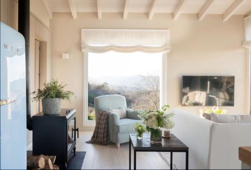 un soggiorno con divano, sedia e finestra di La Guarida Lugás cabañas de lujo a Villaviciosa