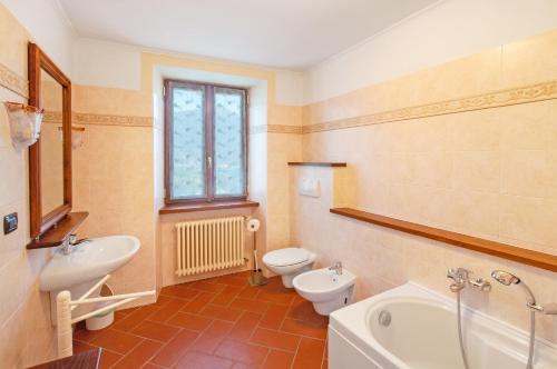 een badkamer met 2 toiletten, een bad en een wastafel bij Il Casale di Marnino in Cremia