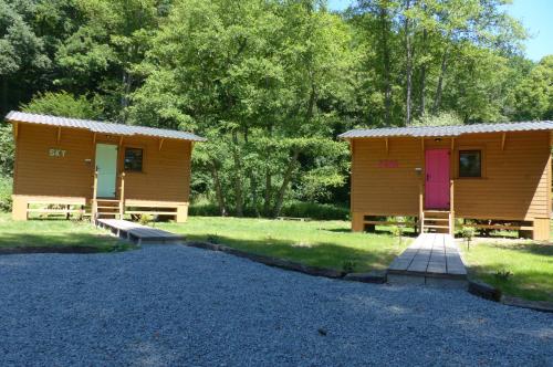 a couple of small wooden huts in the grass at Tiny-river in Falaën