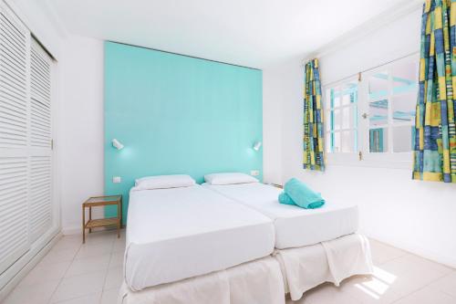 a white bedroom with two beds and a large window at Smy Tahona Fuerteventura in Caleta De Fuste