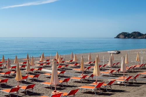 a bunch of chairs and umbrellas on a beach at Hotel Antares in Letojanni
