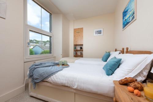 a bedroom with a large white bed with blue pillows at Cormorant Views, Marazion in Marazion