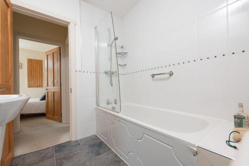 a white bathroom with a sink and a shower at Cormorant Views, Marazion in Marazion