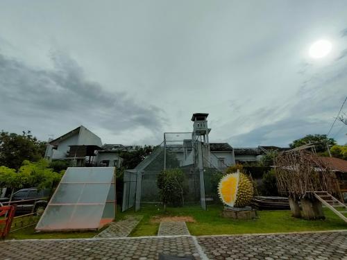 een tuin met een gebouw met een klokkentoren bij Glamping Alas Duren Yogyakarta in Beran-kidul