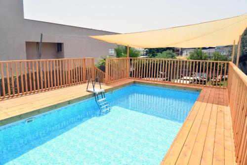 a swimming pool with a wooden deck and a yellow umbrella at Domos Tiberias דומוס טבריה in Tiberias