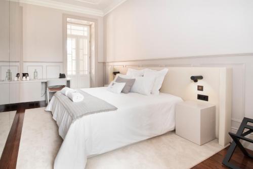 a white bedroom with a large white bed and a table at Casa Noronha Lima - Historic Stay in Alvarenga