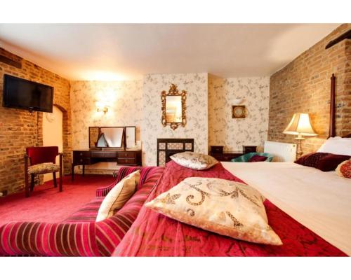 a bedroom with a large bed and a piano at The Rose And Crown Hotel in Wisbech