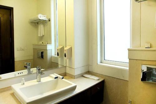 a bathroom with a sink and a large mirror at Inde Hotel Signature Tower in Gurgaon