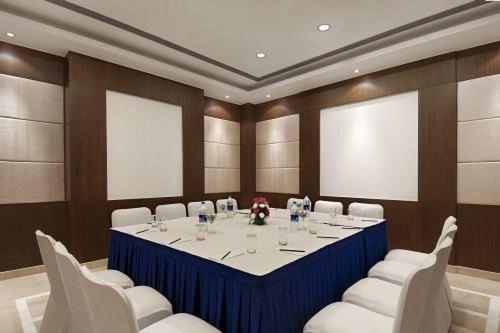 a conference room with a long table and white chairs at Inde Hotel Signature Tower in Gurgaon