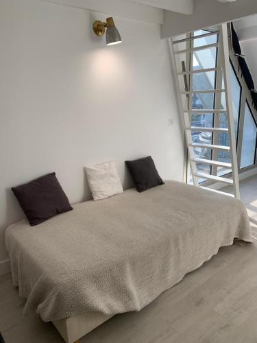 a bed in a white room with a staircase at Blue bay studio terrasse in Deauville