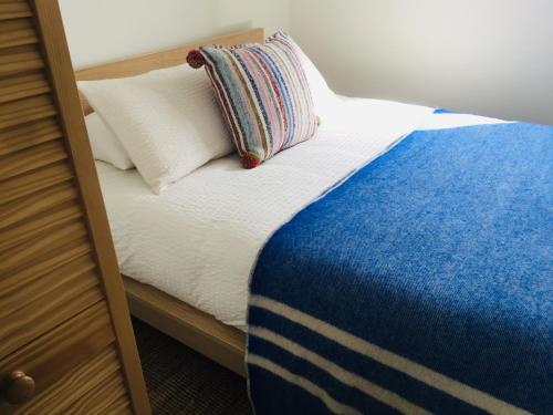 1 cama con manta azul y blanca y almohada en Viv, The, en Wellington