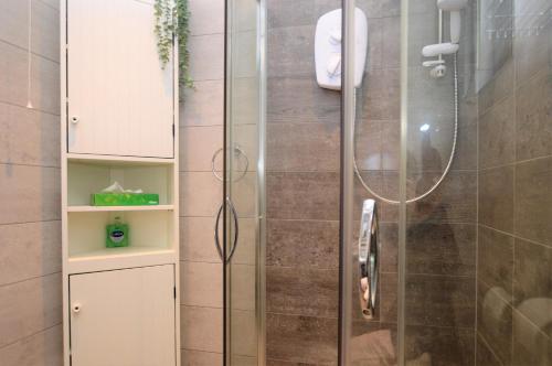 a bathroom with a shower with a glass door at Piper's Lodge in Coirantee