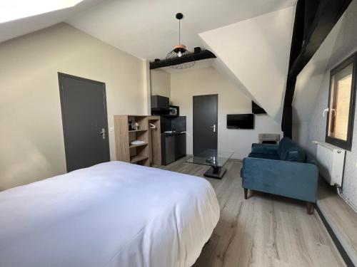 sypialnia z dużym białym łóżkiem i niebieskim krzesłem w obiekcie L'Escale du Vexin w mieście Chaumont-en-Vexin