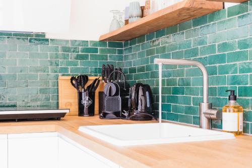 una cocina con fregadero y una pared de azulejos verdes en Kelp, en Egmond aan Zee