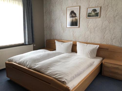 a bedroom with a bed with white sheets and a window at Pension „Alte Straßenmeisterei „ in Hasselfelde