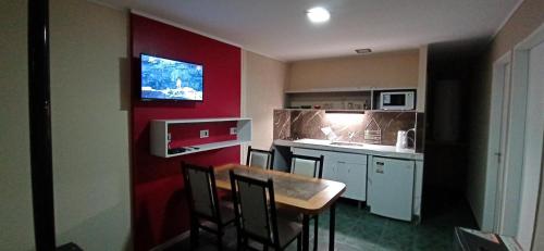 a small kitchen with a table and a red wall at Cabañas Nubes del Plata in Potrerillos