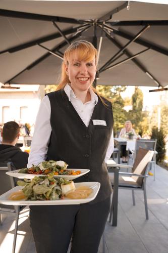 a woman is holding a plate of food at Hünerbein's Posthotel in Schledehausen