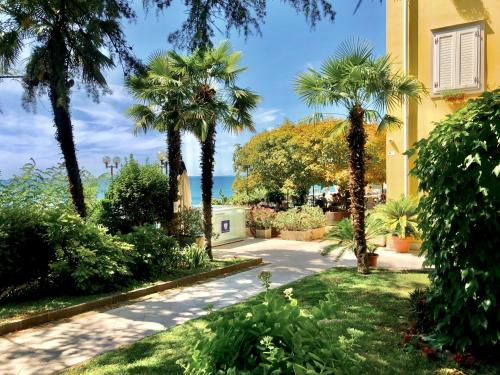a walkway in front of a building with palm trees at Hotel Riviera & Maximilian's in Trieste