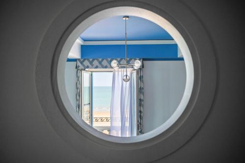 ein rundes Fenster mit Blick auf den Strand in der Unterkunft Casa Bianca Al Mare in Lido di Jesolo