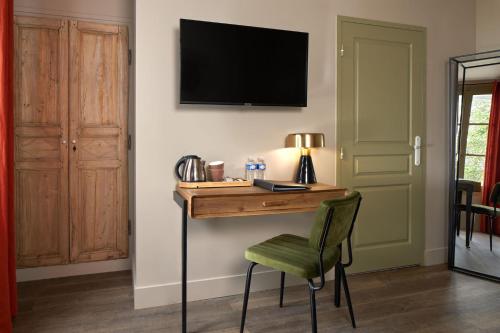 a desk with a green chair and a television on a wall at Hôtel Saint-Alban in Nézignan-lʼÉvêque