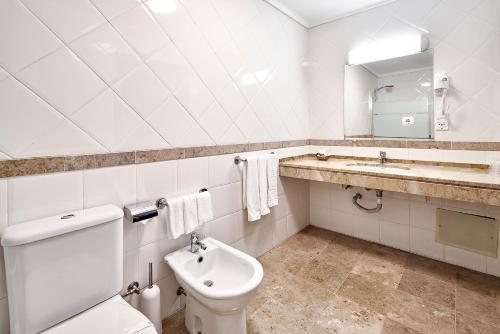 a bathroom with a toilet and a sink and a mirror at Galeria Suite Hotel in Aveiro