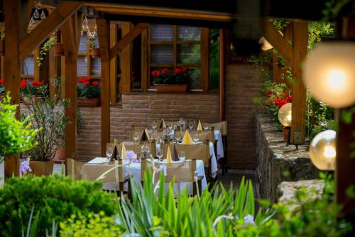 um restaurante com mesas brancas, cadeiras e flores em Hotel Villa Völgy Wellness & Konferencia em Eger