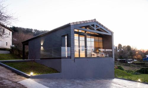 a small house with glass windows on a driveway at La Guarida Lugás cabañas de lujo in Villaviciosa
