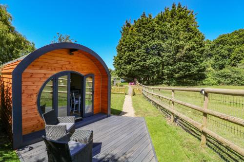 a small wooden cabin with chairs on a wooden deck at Apple Pod in Arundel