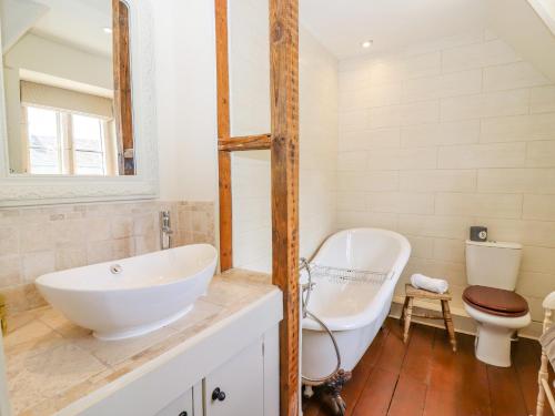 a bathroom with a tub and a sink and a toilet at No 1 Eastington in Cheltenham