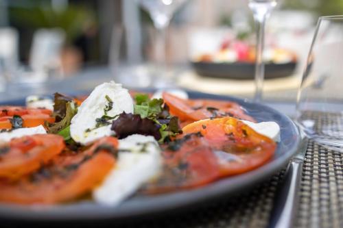 a plate of food with tomatoes on a table at Hôtel restaurant Kyriad Fréjus in Fréjus