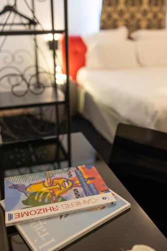 a book sitting on a table next to a bed at Hôtel restaurant Kyriad Fréjus in Fréjus