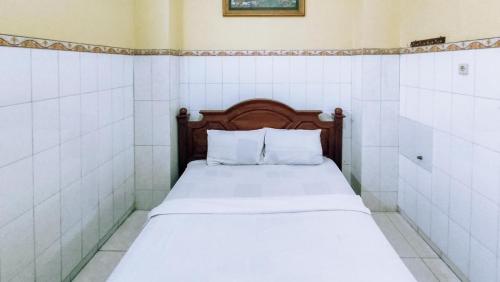 un letto con lenzuola e cuscini bianchi in una stanza di Hotel Shinta 1 near Stasiun Kertosono Mitra RedDoorz a Pelem