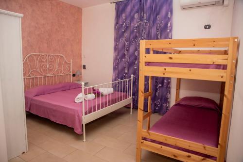 a bedroom with two bunk beds and purple curtains at Il Poggio Veronica in San Nicola