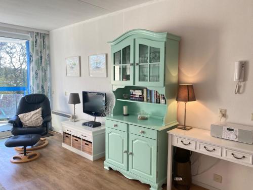 Habitación con armario azul y escritorio con TV. en Badhotel 316, en Callantsoog