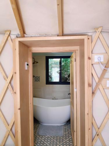 a bathroom with a bath tub and a window at Love Frequency - יורט קסום במתת in Mattat