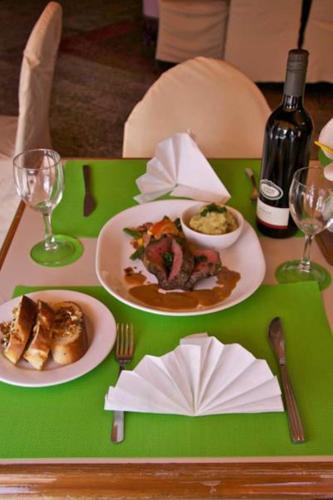 a green table with plates of food and a bottle of wine at Hideaway Hotel in Port Moresby