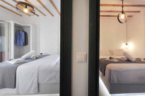 Habitación blanca con 2 camas y espejo. en Droufakos’ home - Beachfront Lux 2BD apt. w. Views, en Sifnos